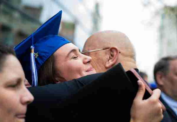 一位毕业生在毕业典礼后拥抱了一位家庭成员.