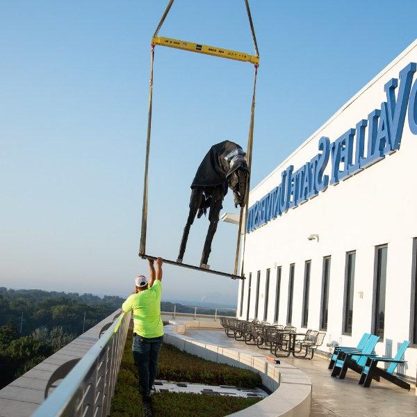 建筑工人伸手去拿由起重机吊在DCIH露台上的雕塑, 皮尤大急流城校区