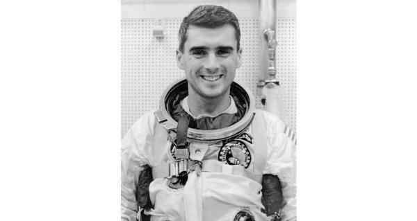 在一张黑白照片中，一个穿着宇航员制服的人微笑着.