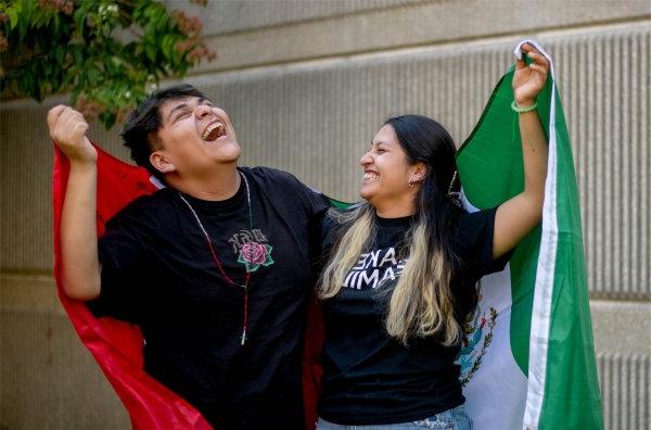  两名大学生举起墨西哥国旗，一起大笑. 