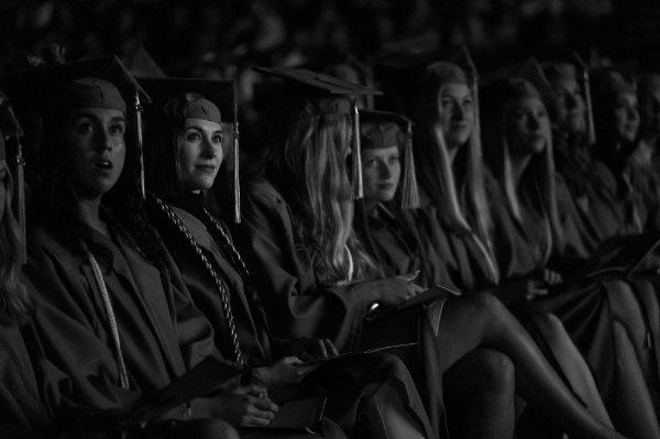  毕业典礼上，大学生们戴着帽子，穿着长袍坐在一起. 