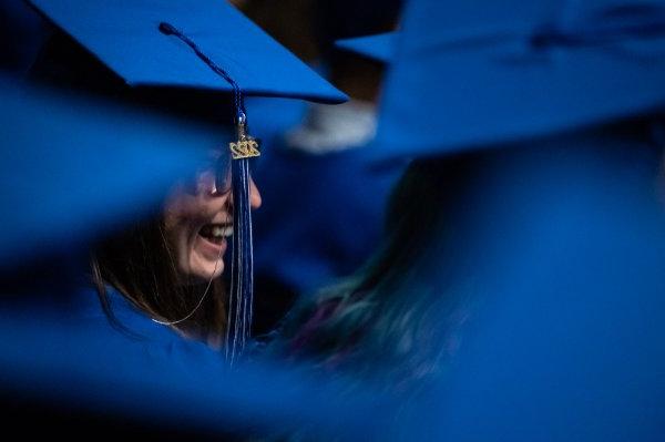  一名大学生笑着看着2022年毕业帽上的毕业流苏. 
