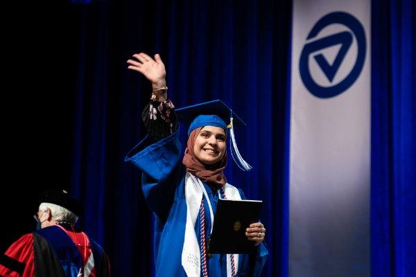  一名大学生拿到毕业证书后在台上挥手. 