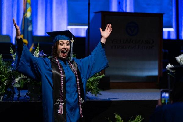  一名大学生在毕业典礼上举手拍照.