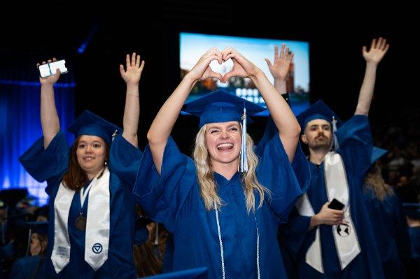  最近的大学毕业生在毕业典礼上举起手臂，做一个心形手势. 