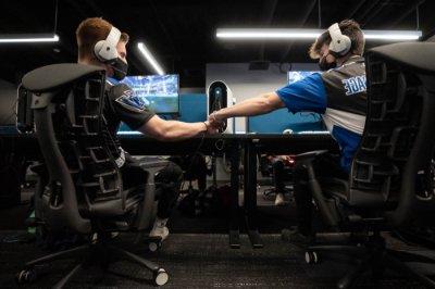 两个电子竞技俱乐部的成员坐在电脑前碰拳