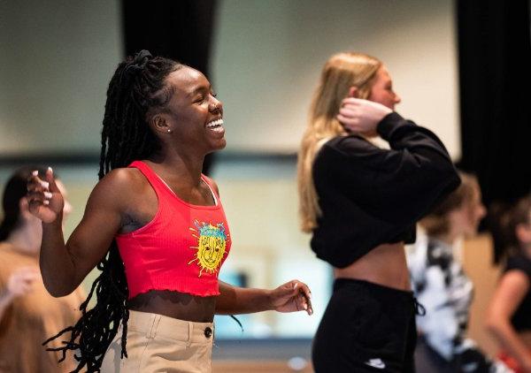 A college student laughs while dancing in a hop hop class.