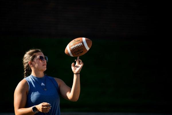 A college student twirls a football on their finger. 