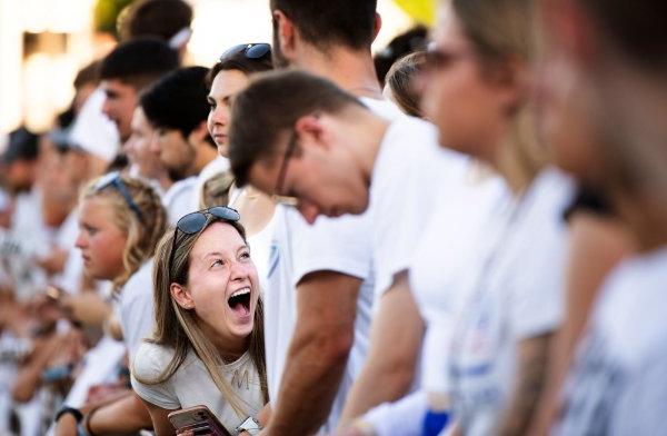  A college student laughs with friends on the sidelines of a football game.