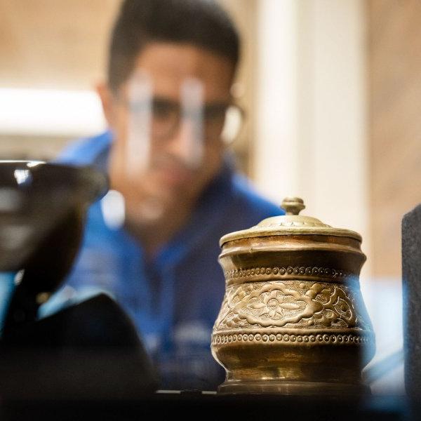 一位戴眼镜的学生透过箱子看一件艺术品，一个伊朗糖碗