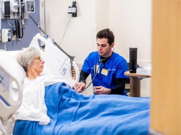 穿着蓝色工作服的护生在医院病床上给病人测血压