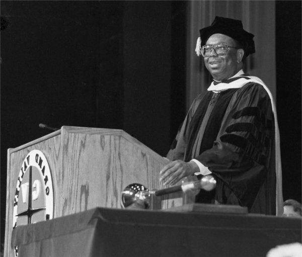 In academic regalia, Bill Pickard stands at podium during a commencement ceremony.