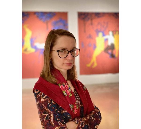 画廊里的Iryna Bilan的肖像，她身后的两幅彩色艺术作品