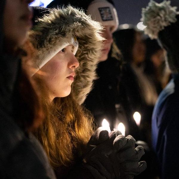 一名身穿保暖外套的大学生在烛光下守夜.