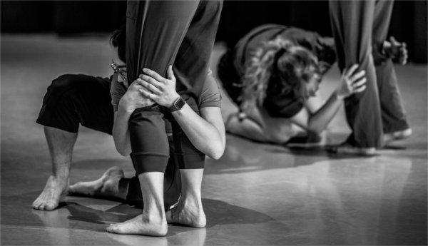 跪在地上的舞者拥抱其他舞者的小腿.
