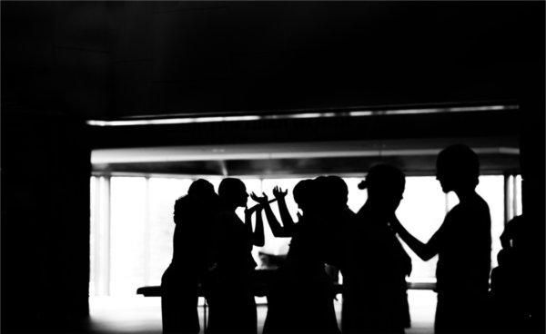 Dancers are silhouetted against a large window.  