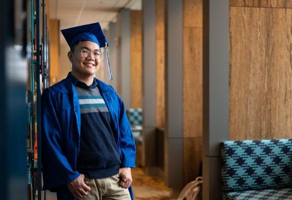 Long Ho poses in academic regalia in the Mary Idema Pew Library