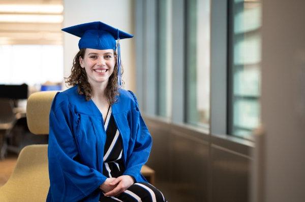 Grace Pallissard poses in academic regalia in the Mary Idema Pew Library 